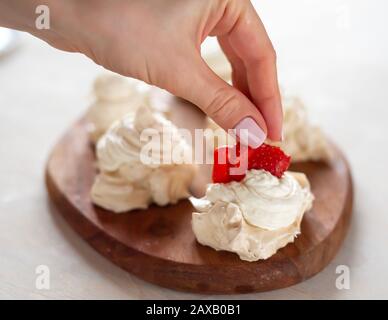 Der Prozess der Herstellung von Pavlova Dessert, die Dekoration der Meringue mit Erdbeeren Stockfoto