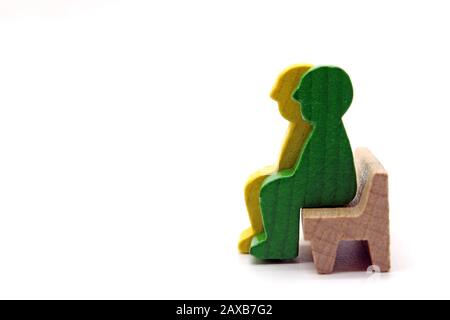 Zwei männliche Holzfiguren, die auf einer Bank sitzen, Konzept, isoliert auf weißem Hintergrund Stockfoto