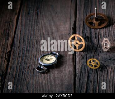 Vintage-Armbanduhr auf einem Holztisch mit Zahnradelementen. Es gibt einen freien Platz für die Beschriftung. Vintage-Stil, nastalgie der Zeit. Stockfoto