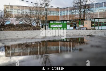 11. Februar 2020, Baden-Württemberg, Geislingen an der Steige: Das Michelberg-Gymnasium spiegelt sich in einer Pfütze wider. Nach der Sanierung der Schule hatten Experten im vergangenen Jahr Mängel festgestellt. Kultusminister Eisenmann (CDU) setzt sich nun für den Erhalt der Schule ein. Foto: Christoph Schmidt / dpa Stockfoto