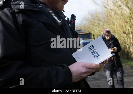 Denham, Großbritannien. Februar 2020. Ein Thames Valley Polizist liest aus einem Buch mit dem Titel "Antiterrorpolicing", während er einem Umweltaktivisten vor Dem Extinction Rebellion eine Warnung ausgibt, der vor einem HGV, der einen JCB-Gabelstapler an einen HS2-Standort liefert, "zu Fuß Unterwegs" gewesen war. Der Aktivist wurde daraufhin verhaftet. Credit: Mark Kerrison/Alamy Live News Stockfoto