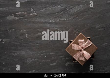 Geschenk, Geschenkbox auf dunklem und sogar schwarzem texturalen Hintergrund. Copyspace. Stockfoto