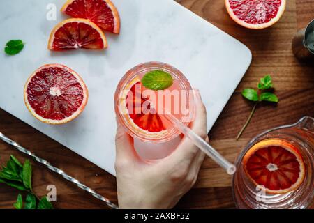 Erfrischender kalter Sommercocktail mit Blutorange und Minze auf einem Marmor-Tablett. Draufsicht, flache Laienzusammensetzung. Stockfoto