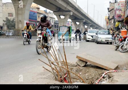 Pendler passieren in der Nähe ein offenes Hauptloch, das zu einem schweren Unfall führen kann, der die Nachlässigkeit der betroffenen Abteilung zeigt, im Komitee Chowk in Rawalpindi am Dienstag, 11. Februar 2020. Stockfoto