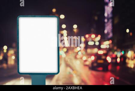 Unbeschriftete Außenblatt-Mockup auf der Stadtstraße nachts mit Ampeln, leerem Werbebanner in städtischem Umfeld Stockfoto