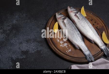 Frische rohe ganze Seebarsch. Raw Wolfsbarsch Fisch mit Gewürzen und Kräutern Zutaten. Ansicht von oben mit der Kopie. Stockfoto