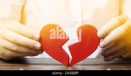 Ein Mann sammelt ein rot gebrochenes Herz. Valentinstag Konzept. Liebe und Beziehungen. Familienpsychotherapeutendienste. Abstimmung. Die Familie retten Stockfoto