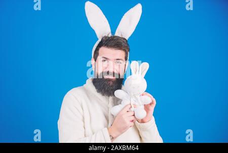 Respekt vor Traditionen. Osterhase. Mann trägt einen kuscheligen Plüschanzug. Lustiger Hünenmann mit Bart und Schnurrbart. Konzept des Ostersymbols. Kerl bärtiger Flusspferd süßer sanfter, bunter langer Ohren blauer Hintergrund. Stockfoto