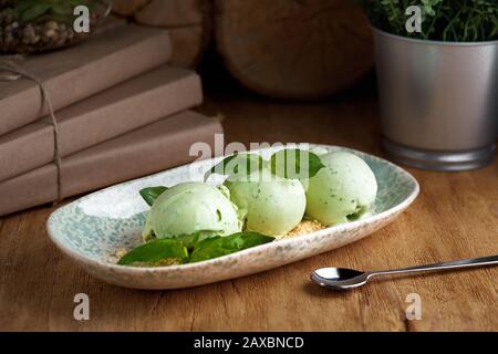 Hausgemachte Eiscreme aus grünem Basilikum auf Holztisch, selektiver Fokus. Stockfoto