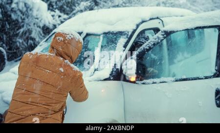 Auto auf der Straße im Schnee stecken, Leute versuchen, es zu nehmen.Transportkonzept. Stockfoto