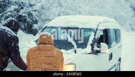 Auto auf der Straße im Schnee stecken, Leute versuchen, es zu nehmen.Transportkonzept. Stockfoto