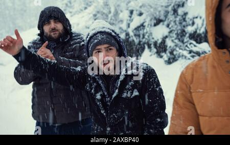 Während es an einem Wintertag schneit, machen die kalten Männer ein Handzeichen, um den Bus zu stoppen.Transportkonzept im Winter. Stockfoto