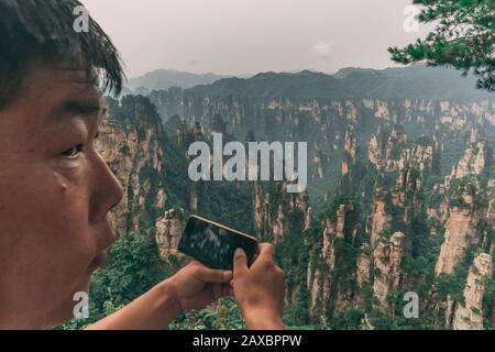 Zhangjiajie, China - August 2019: Chinesische Touristen fotografieren auf Mobiltelefonen auf dem Aussichtspunkt in der Tianzi Bergkette, Avatar Bergwelt Stockfoto