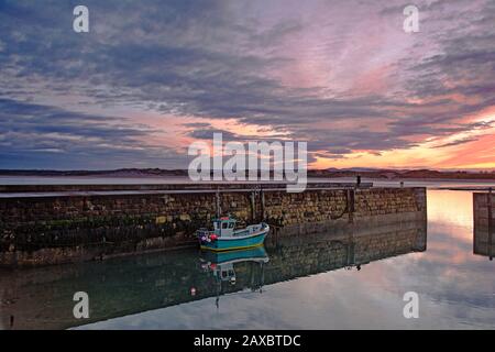 Angelstiefel entlang der Anlegemauer unter dramatischem Sonnenaufgang Stockfoto