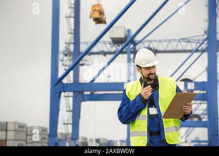 Hafenarbeiter mit Walkie-Talkie und Clipboard auf der Werft Stockfoto