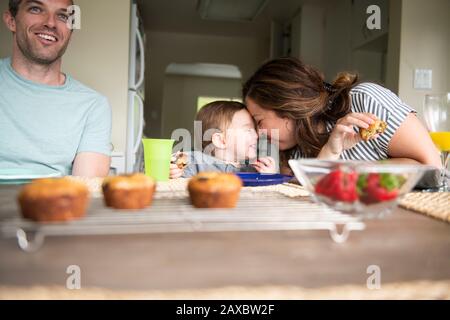 Glückliche Mutter und Tochter reiben Nasen am Küchentisch Stockfoto