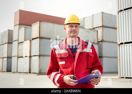 Portrait selbstbewusster Hafenarbeiter mit Clipboard und Walkie-Talkie auf der Werft Stockfoto