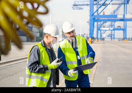 Hafenarbeiter mit Walkie-Talkie und Clipboard Meeting auf der Werft Stockfoto