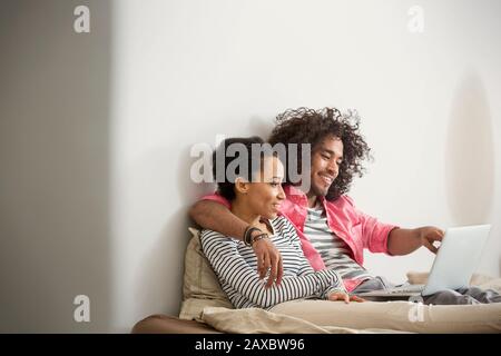 Fröhliches, liebevolles Paar mit Laptop im Bett Stockfoto