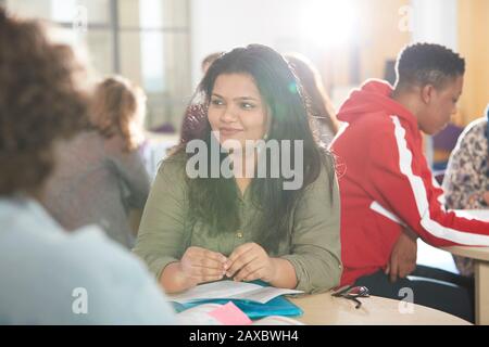 Lächelnde junge Studentin des College, die mit Klassenkameraden studiert Stockfoto