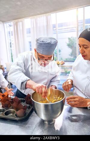 Koch hilft jungen Mann beim Dacken-Syndrom in der Back-Klasse Stockfoto