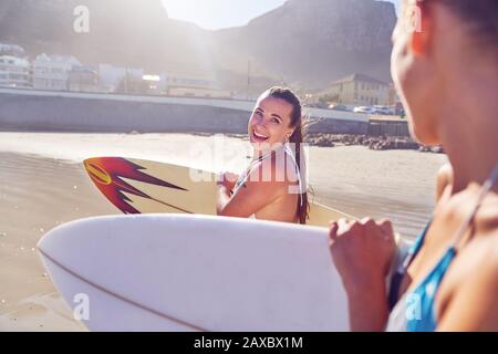 Fröhliche junge Surferinnen Freunden sich mit Surfbrettern am Strand an Stockfoto