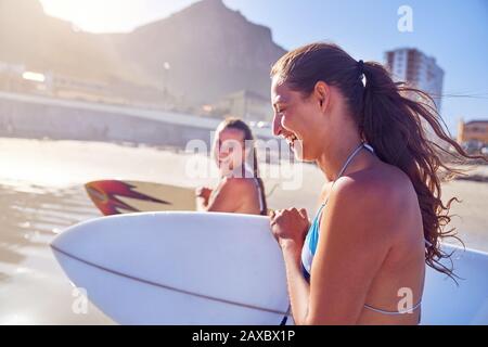 Fröhliche junge Frauen Freunden sich mit Surfbrettern am sonnigen Strand an Stockfoto