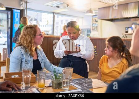 Junger weiblicher Server mit Down-Syndrom, der Kundenbestellung übernimmt Stockfoto