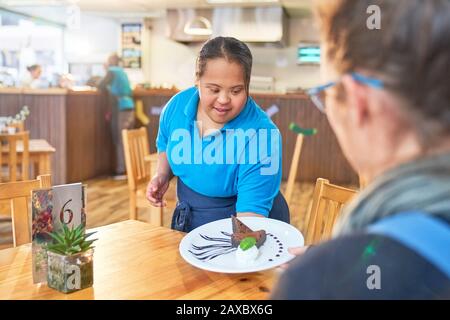 Junge Frau mit Down-Syndrom, die Dessert im Café serviert Stockfoto