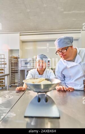 Studenten mit Down-Syndrom, die Teig in der Küche messen Stockfoto