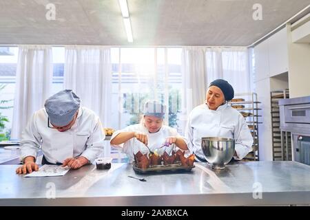 Koch und Studenten mit Down-Syndrom, die Muffins in der Küche backen Stockfoto