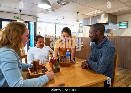 Junger weiblicher Server mit Down-Syndrom, der Getränke im Café serviert Stockfoto