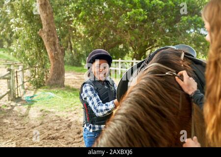 Portrait selbstbewusstes Mädchen bereitet Sattel für Reiten vor Stockfoto