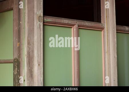 Alte abisolierte Fensterrahmen mit grünen Glasscheiben Stockfoto