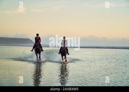 Junge Frauen reiten in der Meeresbrandung Stockfoto