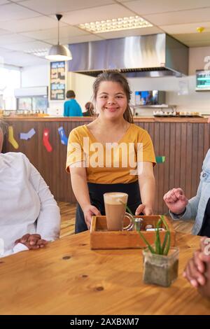 Portrait fröhlicher junger weiblicher Server mit Down-Syndrom im Café Stockfoto