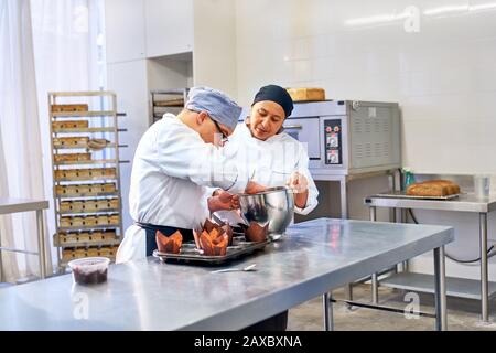 Koch und Student mit Down-Syndrom, der Muffins in der Küche backt Stockfoto