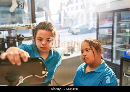 Junge Frauen mit Down-Syndrom arbeiten im Café Stockfoto