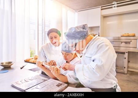 Koch und Studenten mit Down-Syndrom, die digitales Tablet in der Küche verwenden Stockfoto