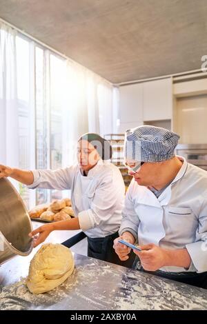 Koch und Student mit Daisen-Syndrom, das Brot in der Küche backt Stockfoto