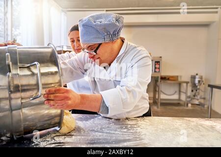 Junger männlicher Student mit Down-Syndrom-Backen in der Küche Stockfoto