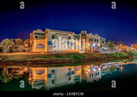 Ägyptische Häuser an der Seite der Lagune, die nachts im Wasser reflektiert werden, el Gouna, Ägypten, 16. Januar 2020 Stockfoto