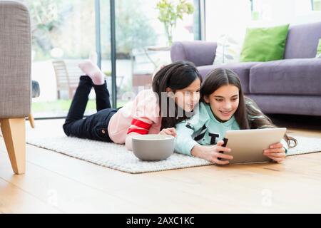 Mädchen, die Filme mit digitalem Tablet auf dem Boden des Wohnzimmers ansehen Stockfoto