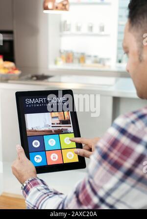 Mann steuert Smart Home Navigationssystem vom digitalen Tablet in der Küche Stockfoto