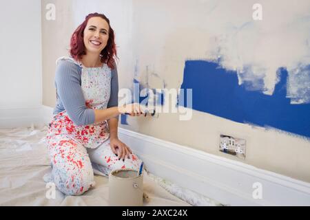 Portrait glückliche Frau in Overalls Malwand Stockfoto