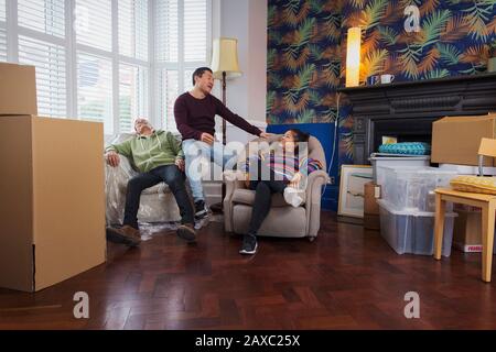 Freunde, die eine Pause vom Umzug machen und sich im Wohnzimmer entspannen Stockfoto