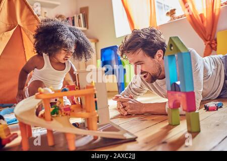 Vater und kleine Tochter, die mit Spielzeug auf dem Boden spielen Stockfoto