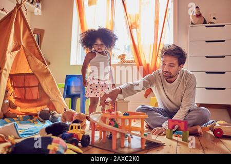 Vater und Tochter spielen mit Spielzeug auf Etage Stockfoto