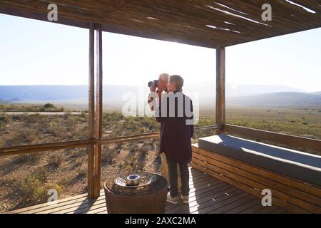 Älteres Paar mit Kamera auf sonnigen Safari-Kabinenbalkon Stockfoto