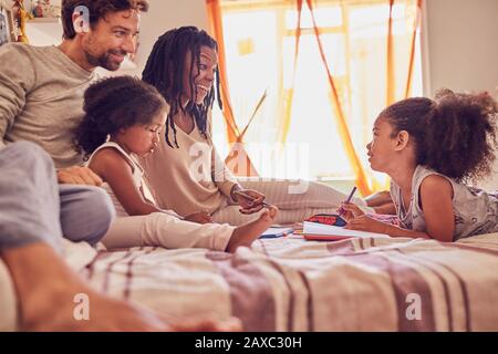 Junge Familie färbt sich auf dem Bett Stockfoto